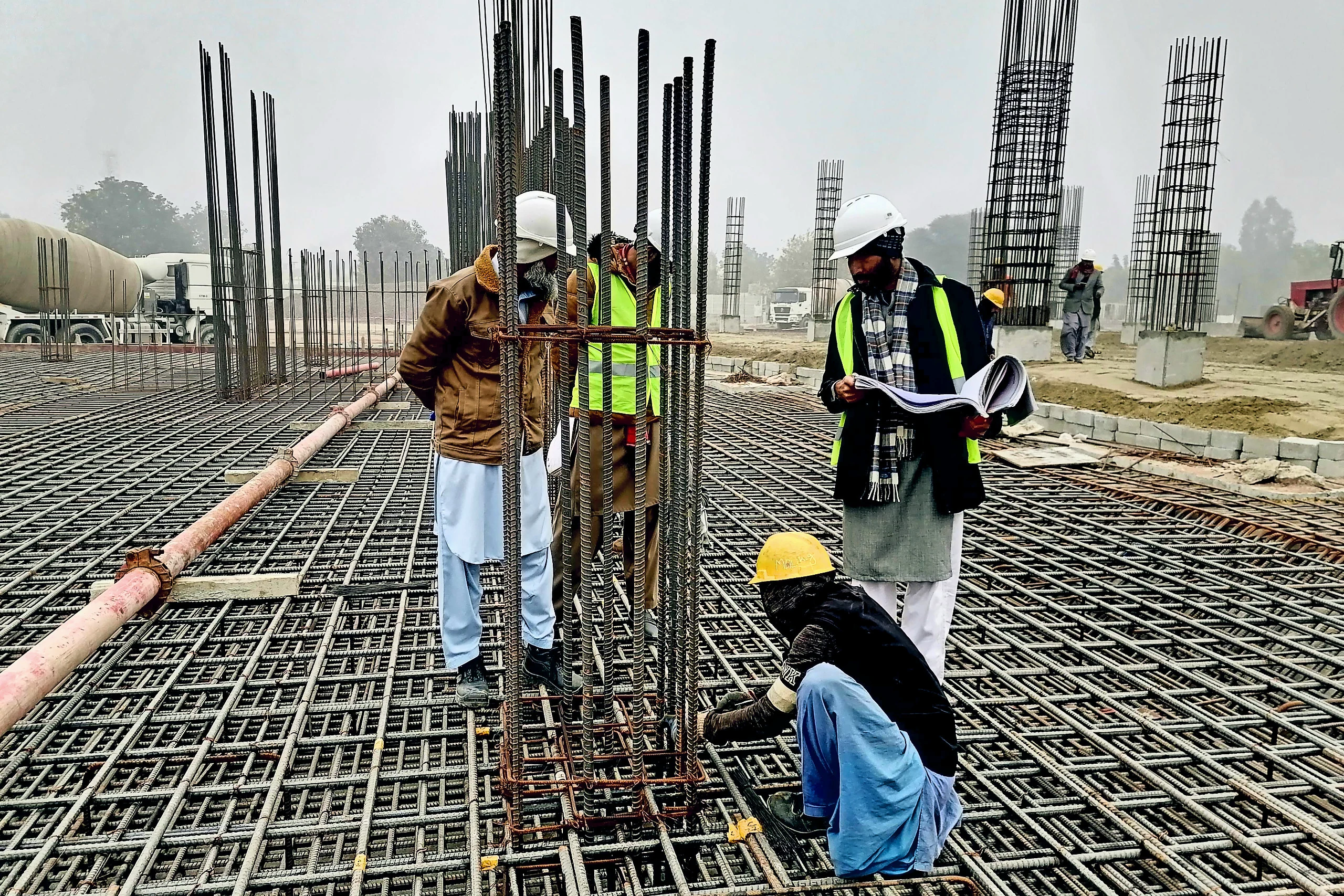 Two engineers on an infrastructure project site, reviewing a set of drawings together